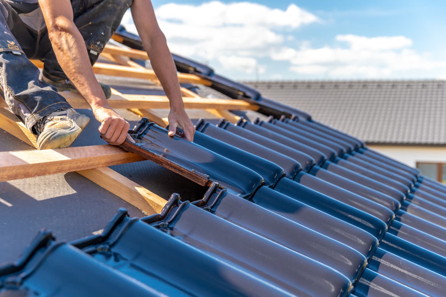 Dakwerker plaatst nieuwe blauw-geglazuurde dakpannen